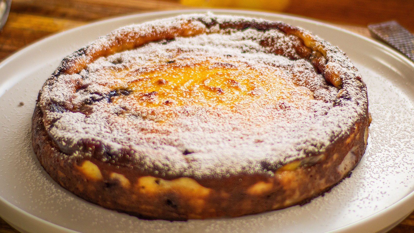 This recipe is based on the Corsican Fiadone or Fiadoni cheesecake which has no bottom layer. That’s what makes it so simple to make, 10 to 15 minutes maximum. What other cheesecake is that quick! I’ve also added blueberries in the filling so there’s no need to top with anything else except a little icing or powdered sugar. This custard style cake needs to be served cold or room temperature. The Corsican version is usually made with goat’s milk ricotta called “Brocciu” which is stronger in flavour. But any similar cheese will work. You need to use drained ricotta otherwise simply place the fresh cheese in a muslin cloth over a colander and refrigerate a few hours to drain the liquid. The alcohol is optional, but using the zest of two lemons is not, you need that strong lemony flavour to cut through the richness. Ensure there’s still a little wobble in the centre once cooked. One of the simplest cheesecake you can make and so delicious! Enjoy my Baked Ricotta Cheesecake With blueberries.